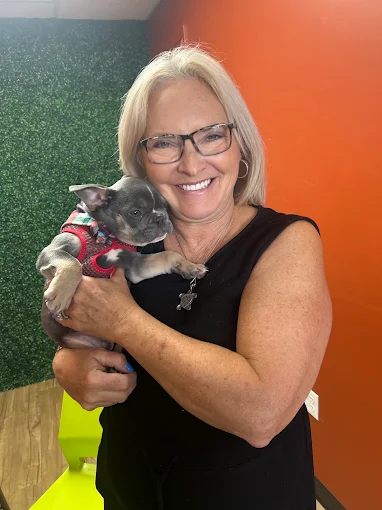 Smiling woman holding a small gray puppy