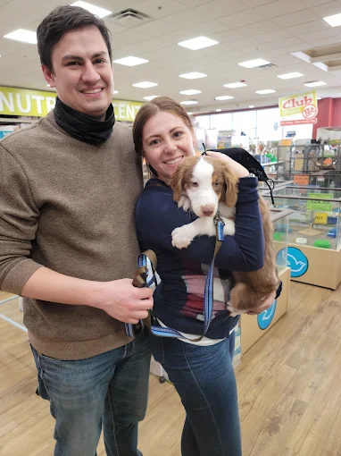 Couple holding a brown and white puppy in a pet store